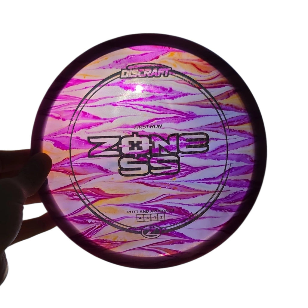 Backlit view of purple and orange hand-dyed Discraft First Run Zone SS in Z plastic